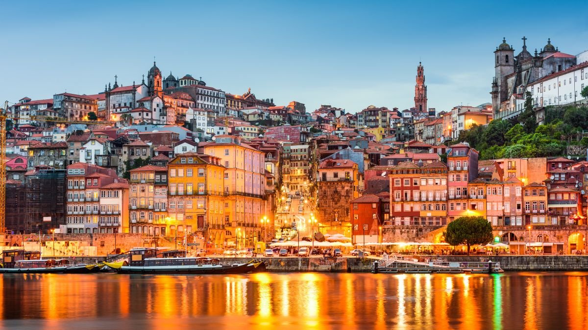 Vista panorâmica de Lisboa ao pôr do sol com o rio Tejo e casas tradicionais, ilustrando a mudança de vida com o Visto D7 para Portugal